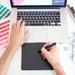 Graphic designer working on a laptop with colour swatches for a small business project