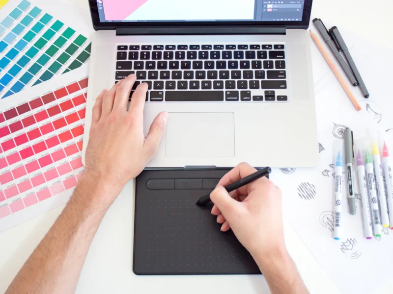 Graphic designer working on a laptop with colour swatches for a small business project