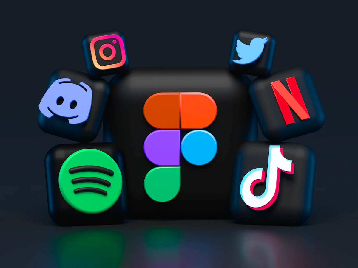 Social media manager creating content on a laptop with a phone showing app icons